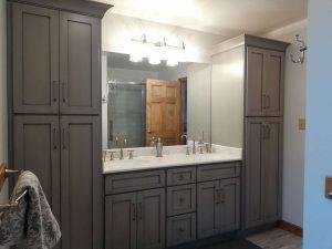 many tall grey cabinets in a bathroom around a sink and mirror built and installed by Creation Cabinetry in Hamburg PA